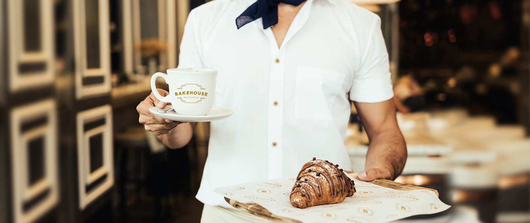 Jacober Creative identity design for Bakehouse Brasserie - Photo of a waitress holding a branded mug and pastry